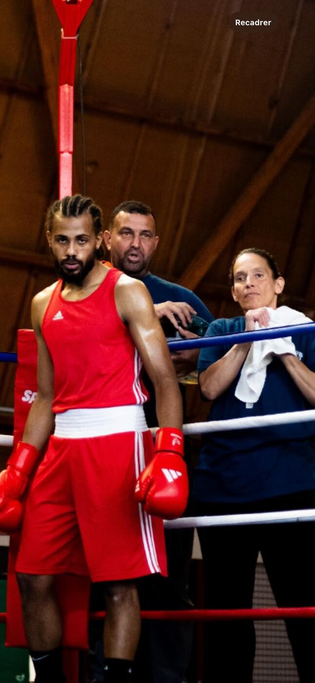 Un boxeur du club dans le coin du ring, encadré par ses deux entraîneurs